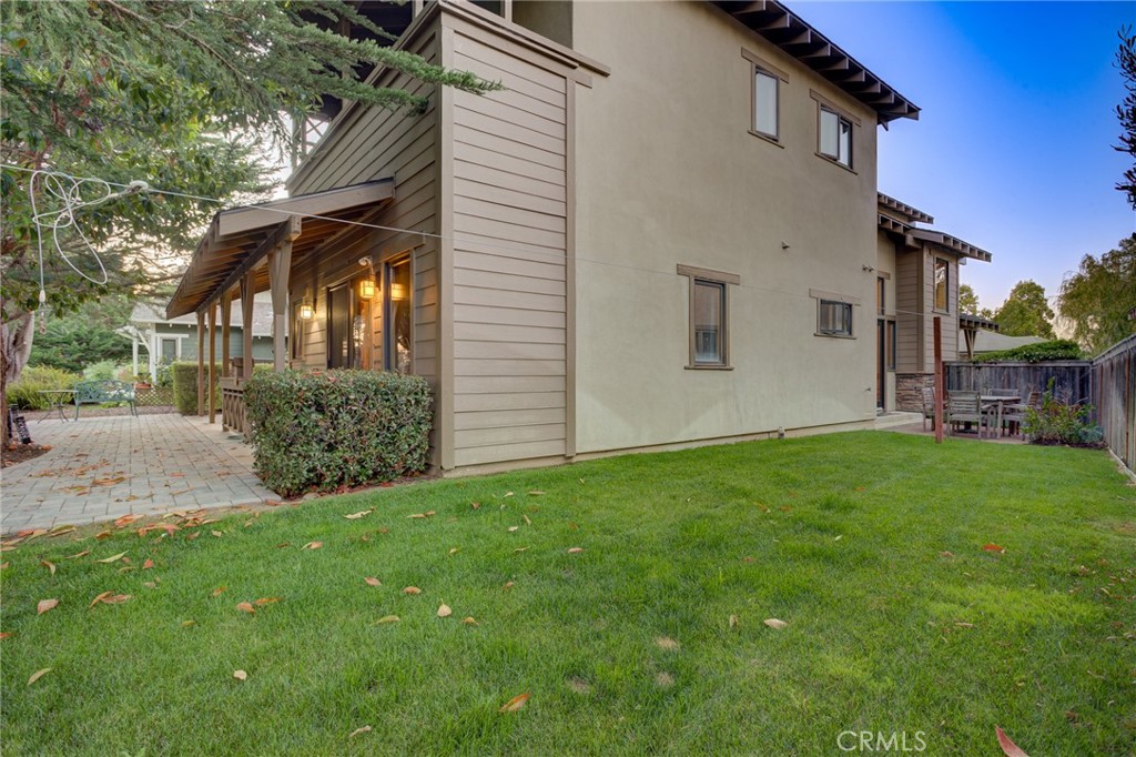Two-story home with covered patio, paved courtyard, and green lawn.