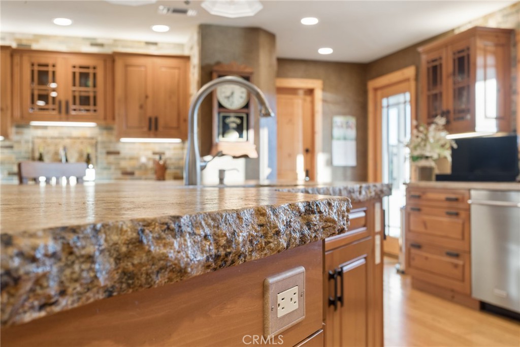 Kitchen with a granite island, warm wood cabinetry, and a tall curved faucet.