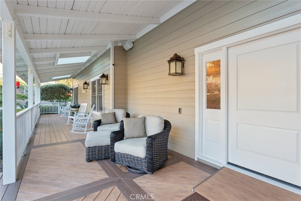 Covered front porch with wicker lounge chairs and white rocking chairs along the walkway.