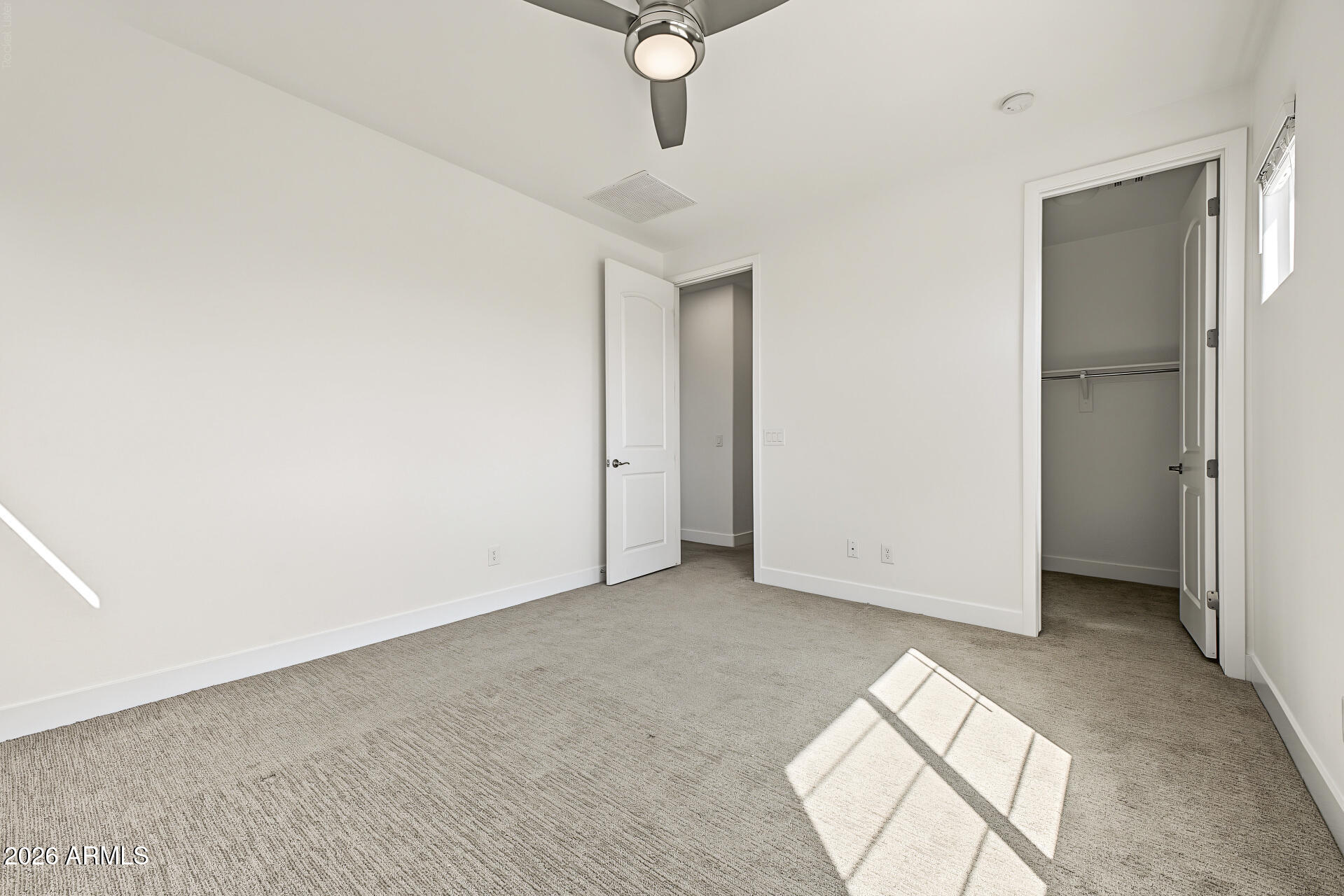 Empty bedroom with carpet, ceiling fan, and open closet.