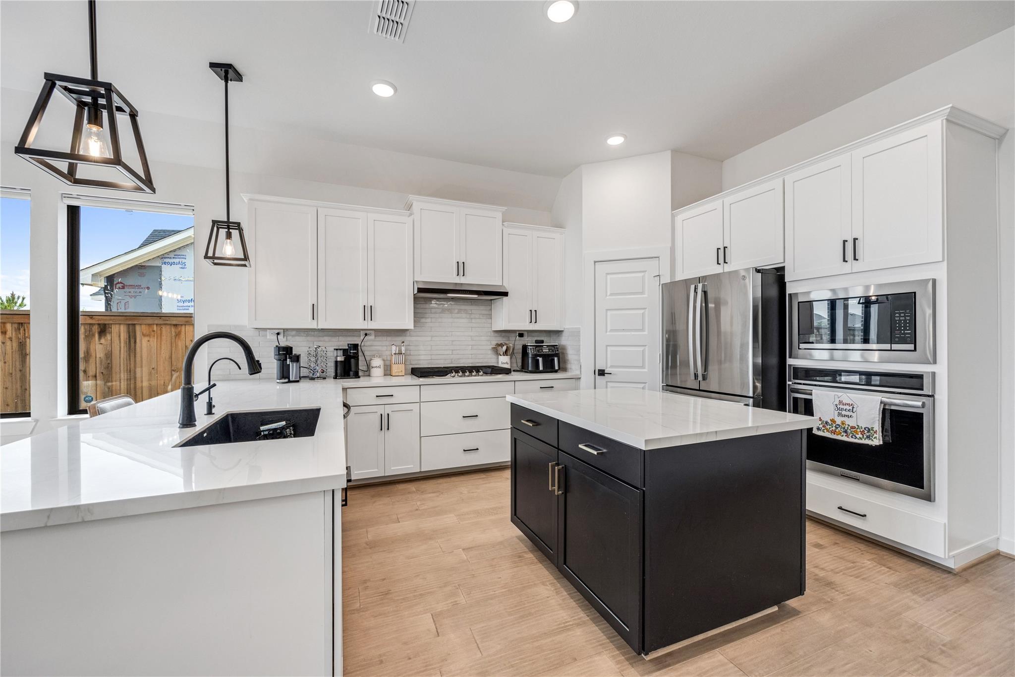 Modern kitchen with white cabinetry, stainless appliances, and a large black island.