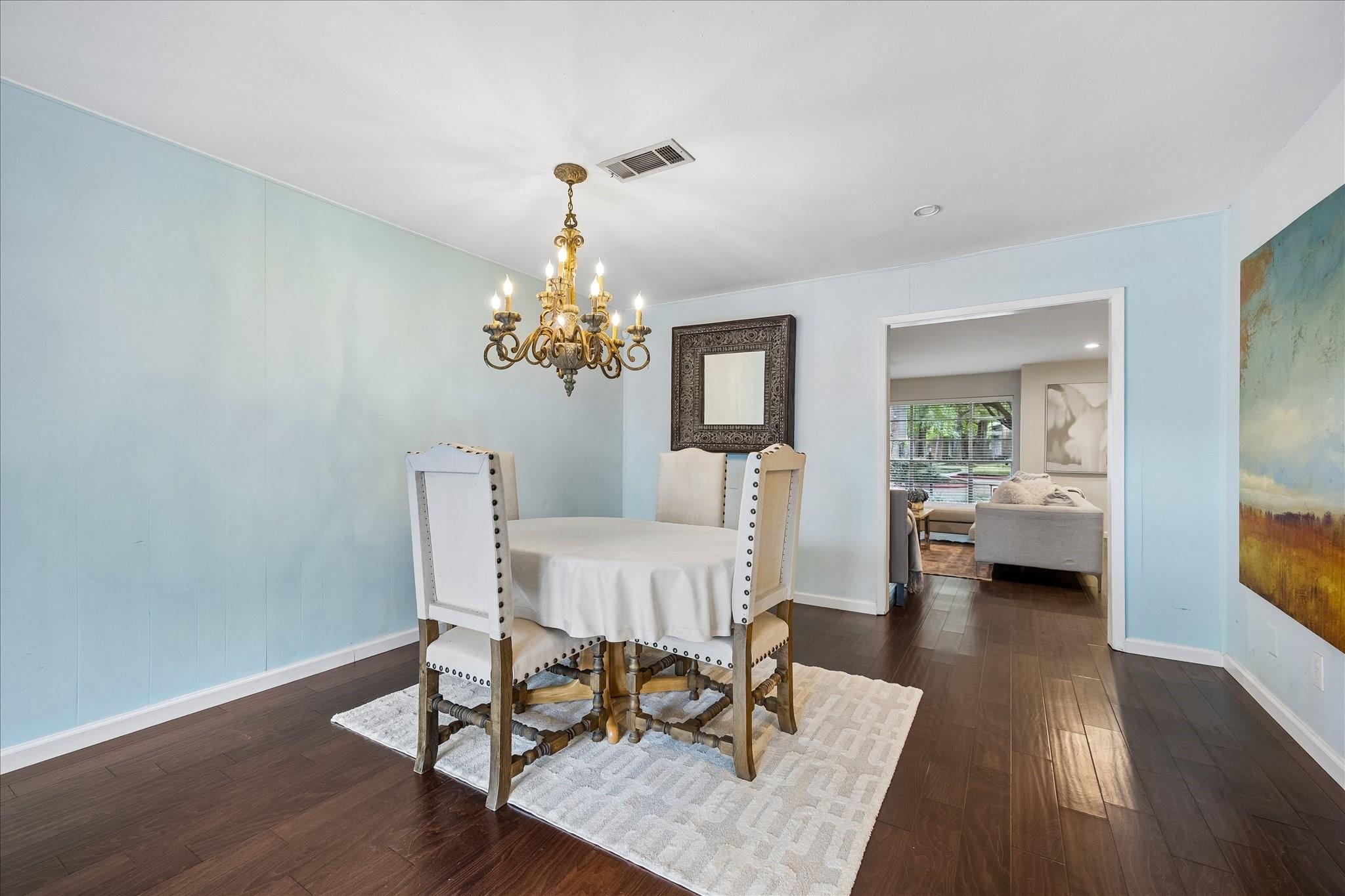 Dining room with a round table, upholstered chairs, and an ornate chandelier.