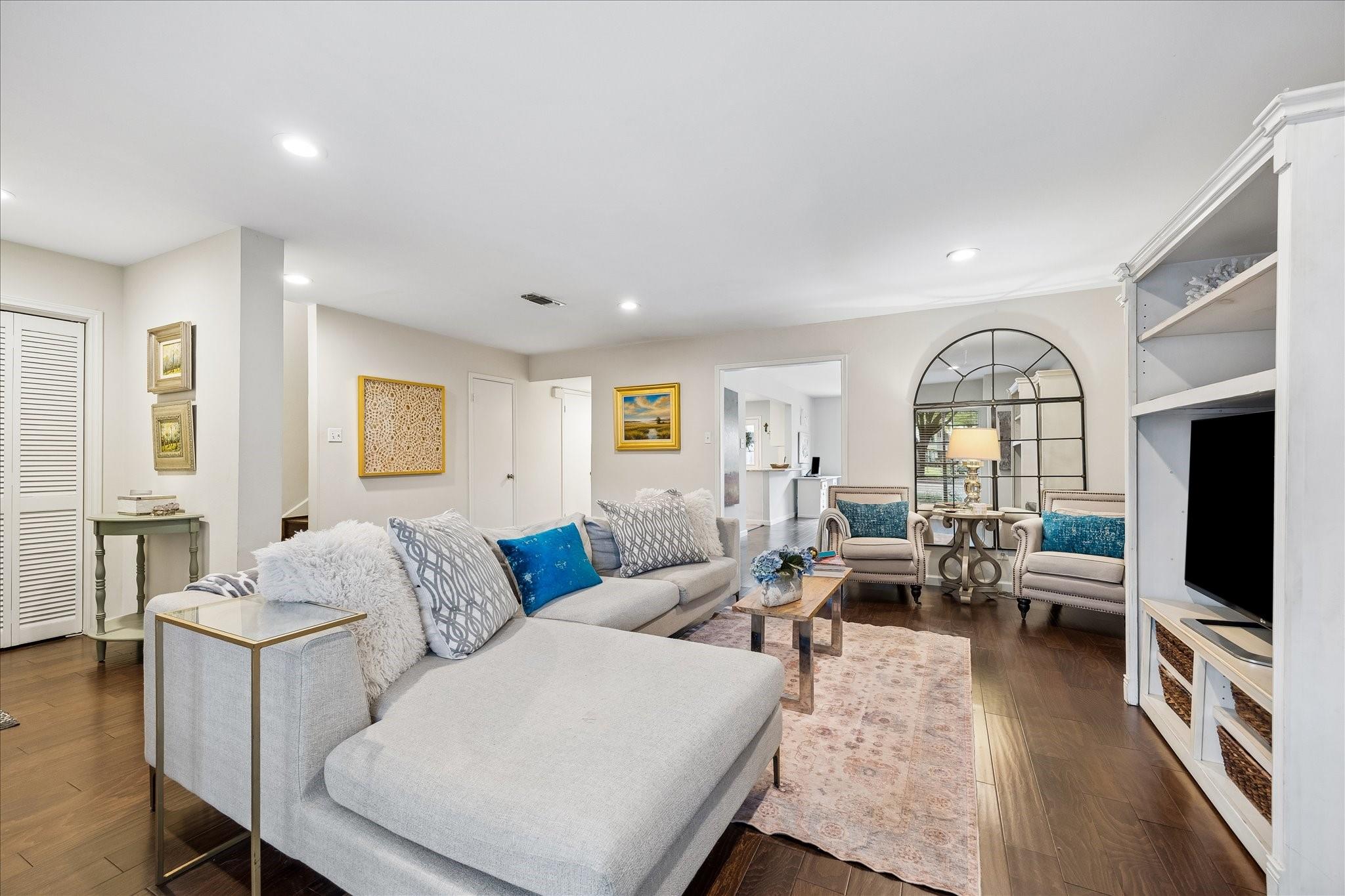 Living room with a large gray sectional, blue cushions, built-in shelving, and an arched mirror.
