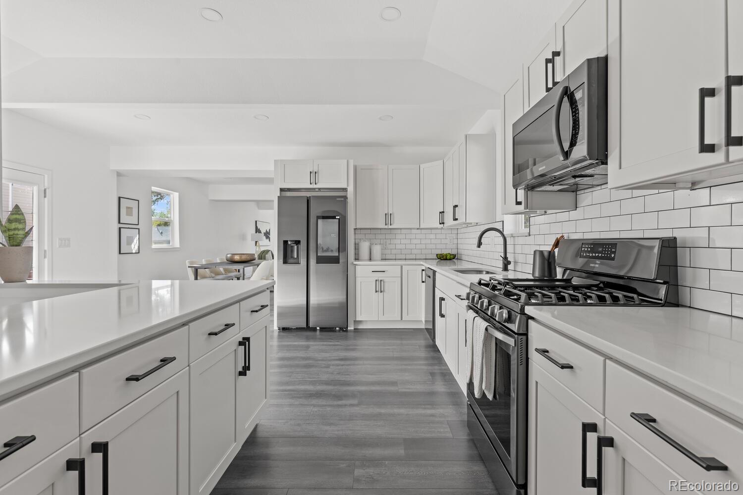 Renovated kitchen with a large white island, stainless steel appliances, and subway tile backsplash.