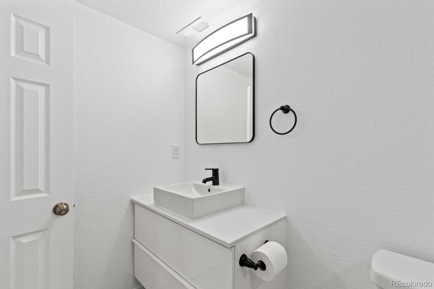 Bathroom vanity with a square vessel sink, black fixtures, and a rectangular mirror.