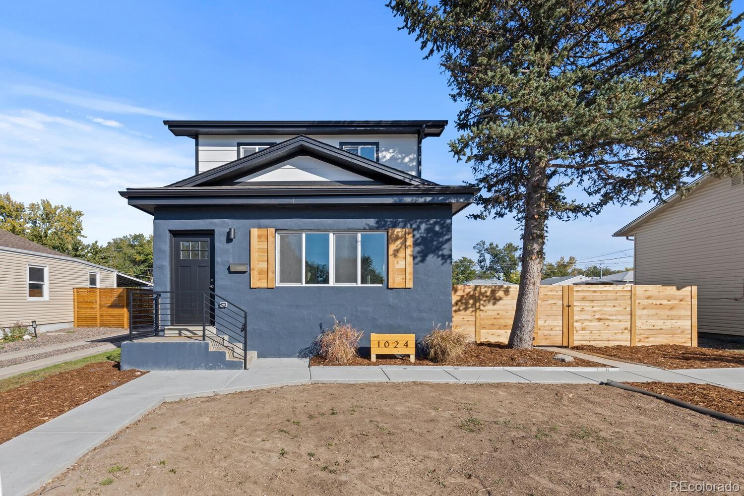 Two-story home with dark blue-gray siding, wood shutters, and a fenced front yard.