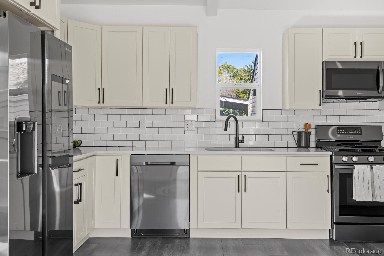 Kitchen with white shaker cabinets, subway tile backsplash, stainless steel appliances, and a window above the sink.