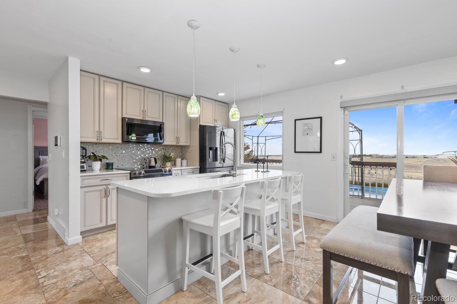 Kitchen with a white island and bar stools, cream cabinets, and sliding doors overlooking a patio.