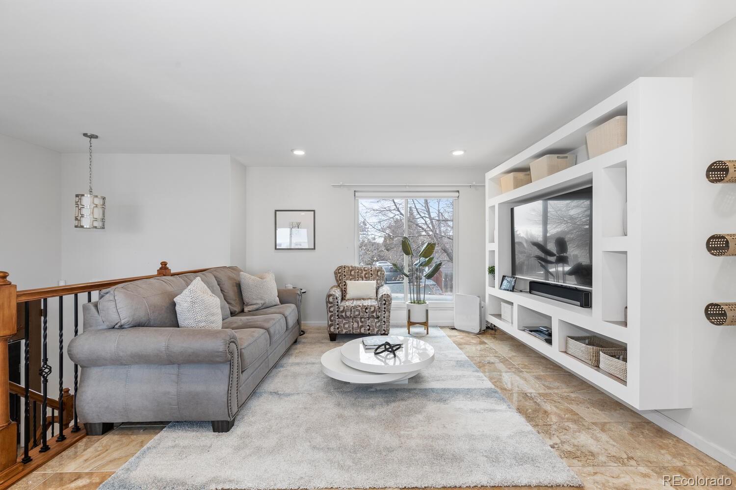 Living room with a gray sectional, white built-in media shelving, and sliding glass door.