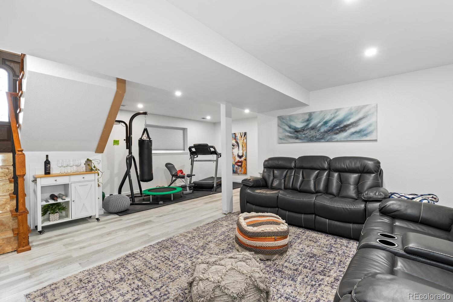 Basement recreation room with leather sofas and a workout area featuring a treadmill and punching bag.