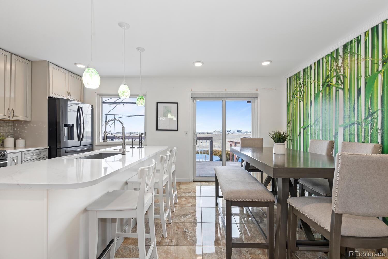 Kitchen and dining area with a large white island, dark table, and green bamboo mural.
