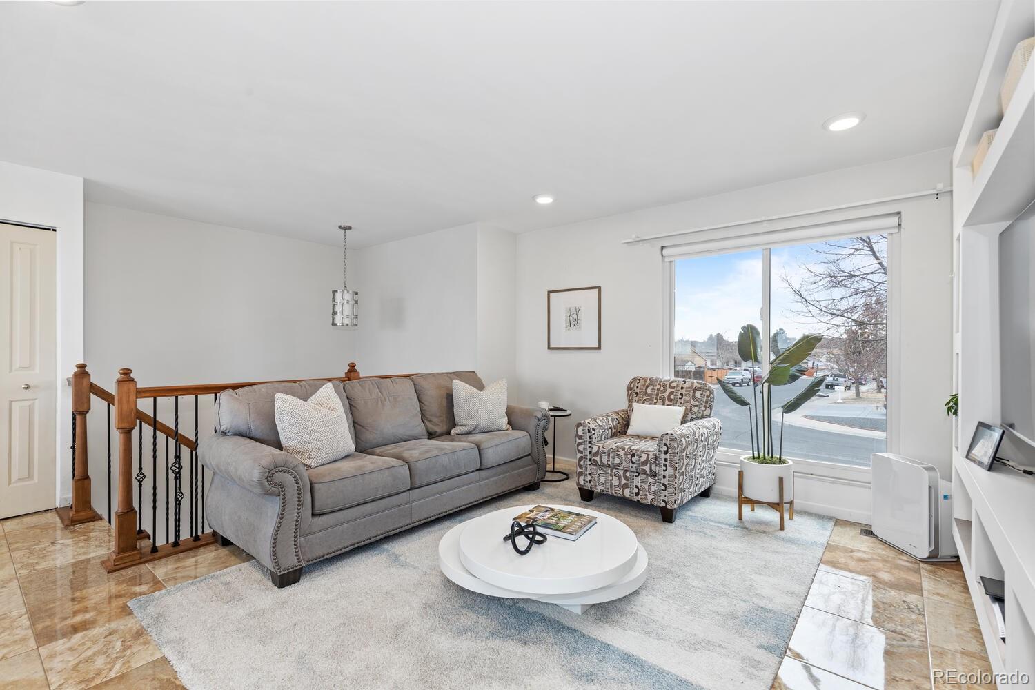 Living room with a gray sofa, patterned armchair, and large street-facing window.