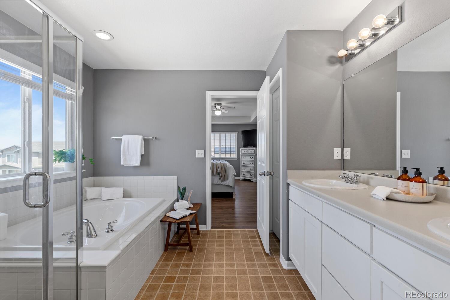 Bathroom with tiled soaking tub, glass shower, and long white vanity.