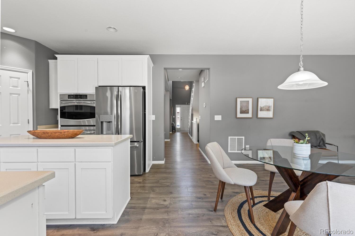 Kitchen and dining area with white cabinetry, stainless steel appliances, and a glass-top table.