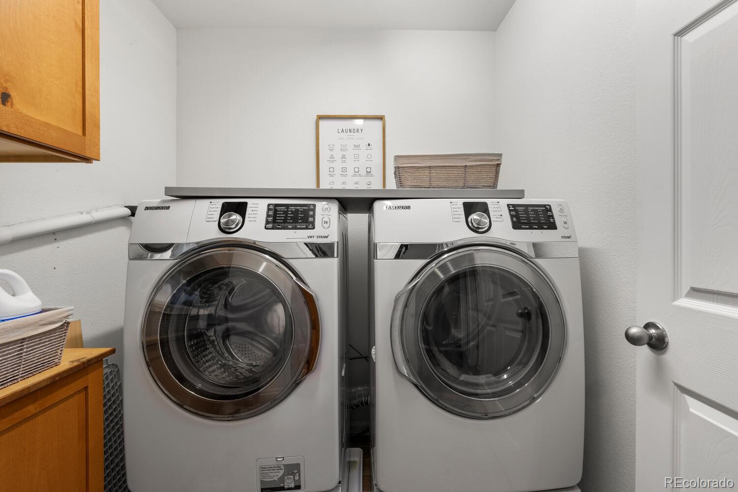 Laundry room with a Samsung front-loading washer and dryer beneath a shelf.