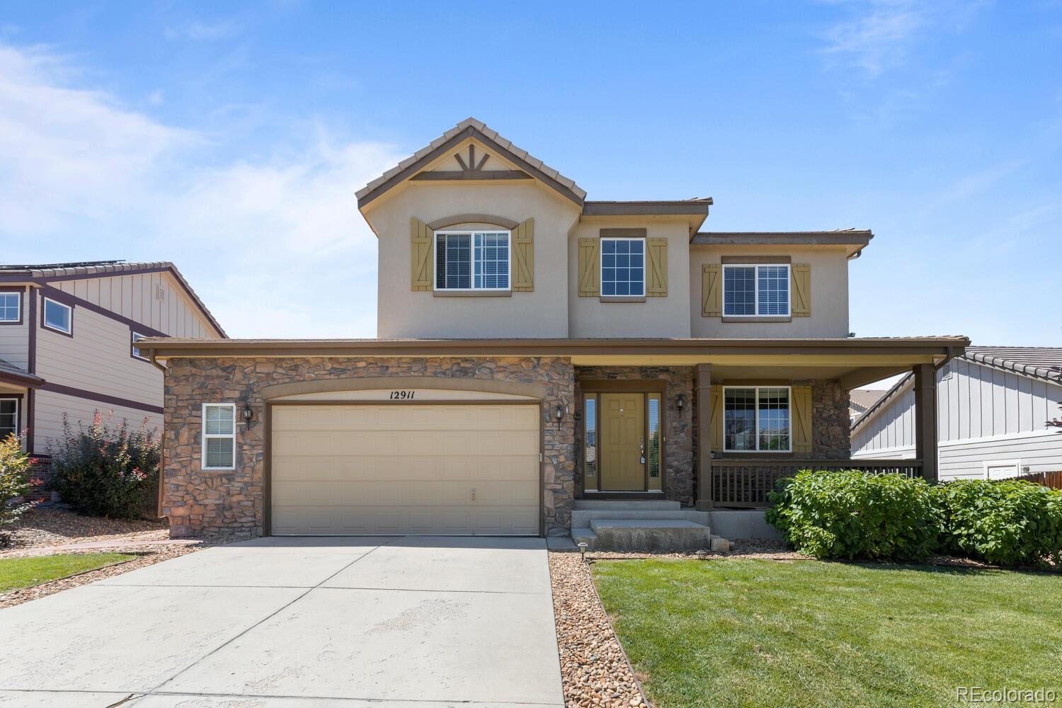 Two-story home with a stone facade, attached garage, and covered front porch.