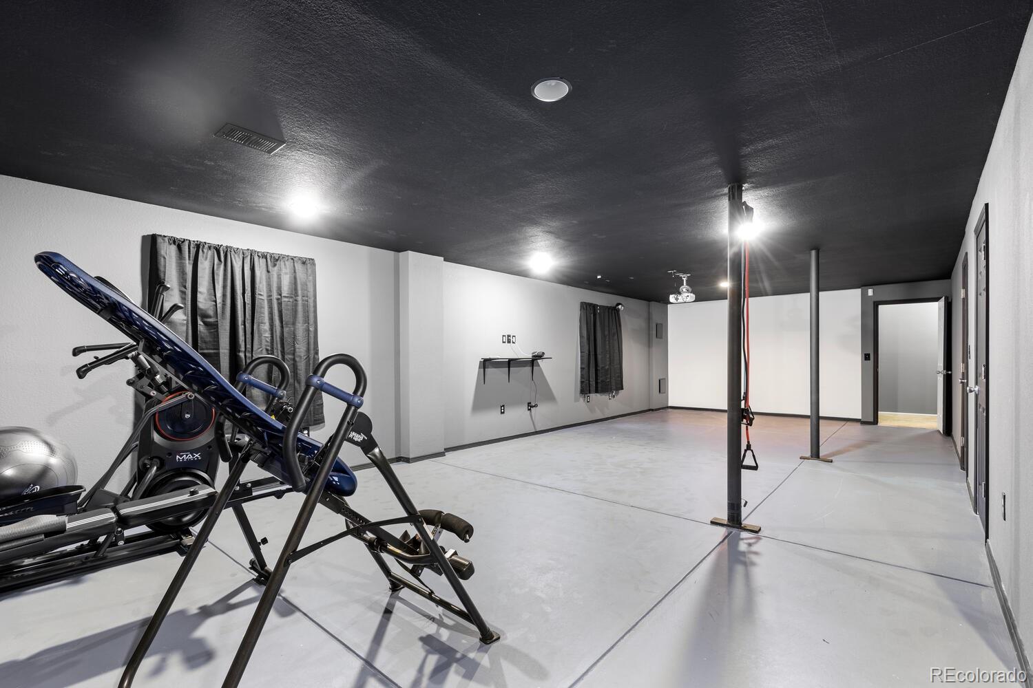 Basement gym with exercise equipment and workout poles in a spacious room.