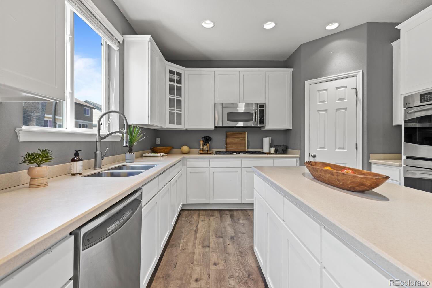 Bright kitchen with white cabinetry, a large island, stainless steel appliances, and a window over the sink.