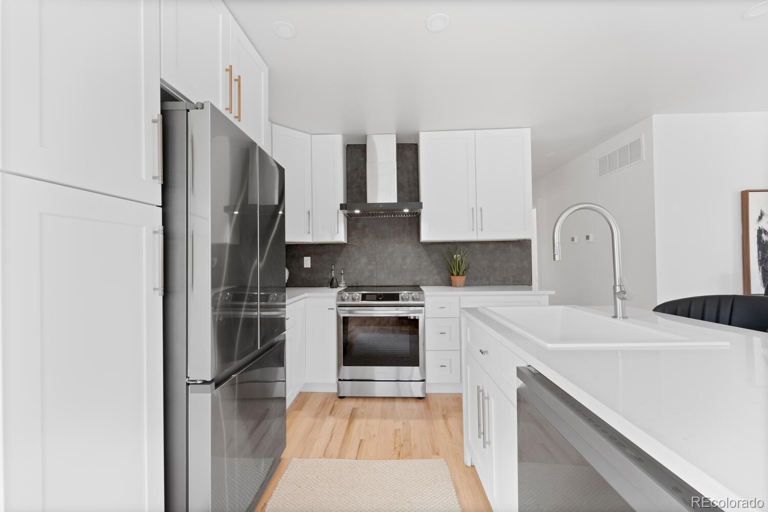 Kitchen with white cabinets, stainless steel appliances, gray backsplash, and a large island.
