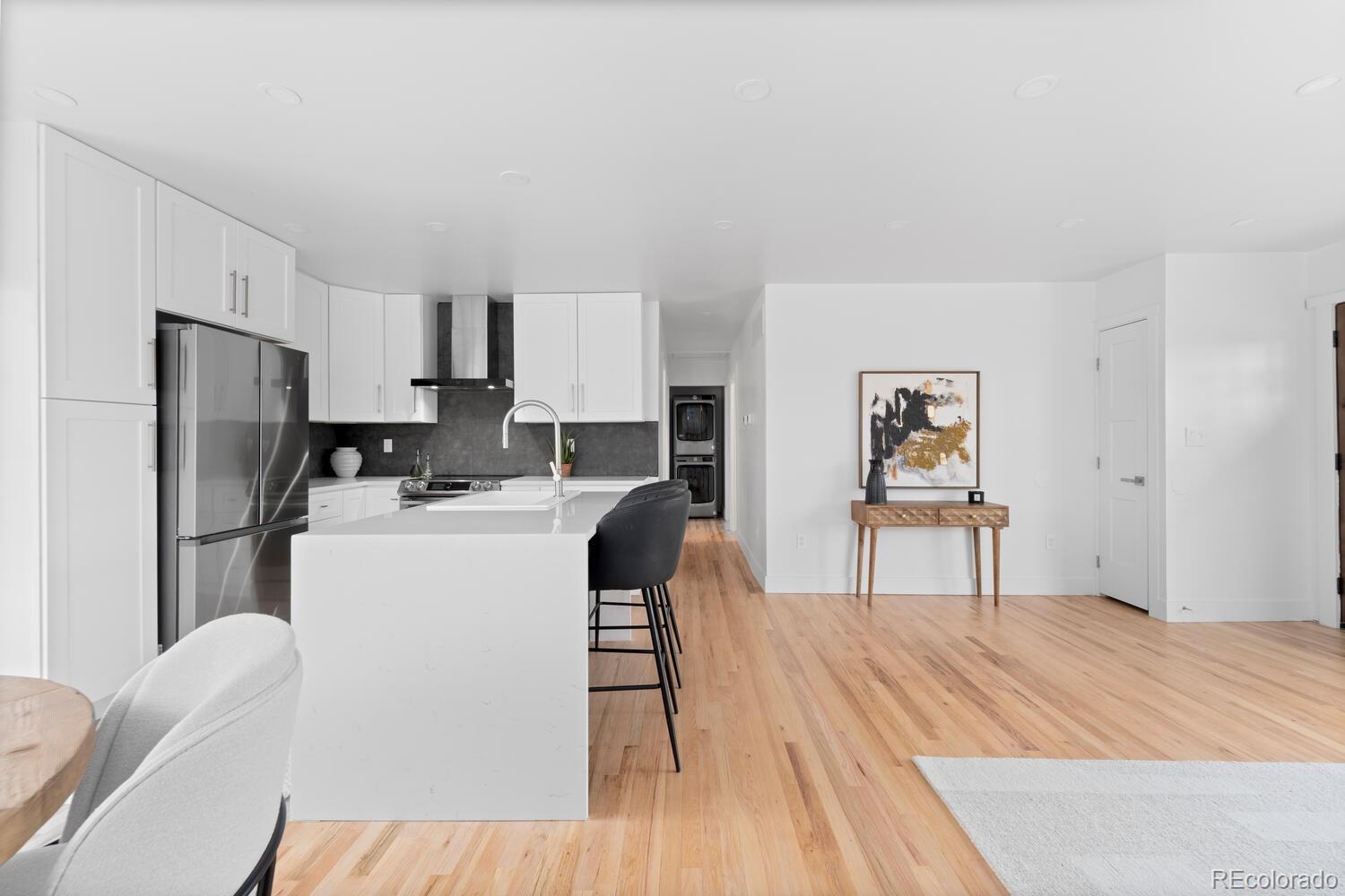 Open-plan kitchen with a large white island, stainless steel appliances, and light wood floors.