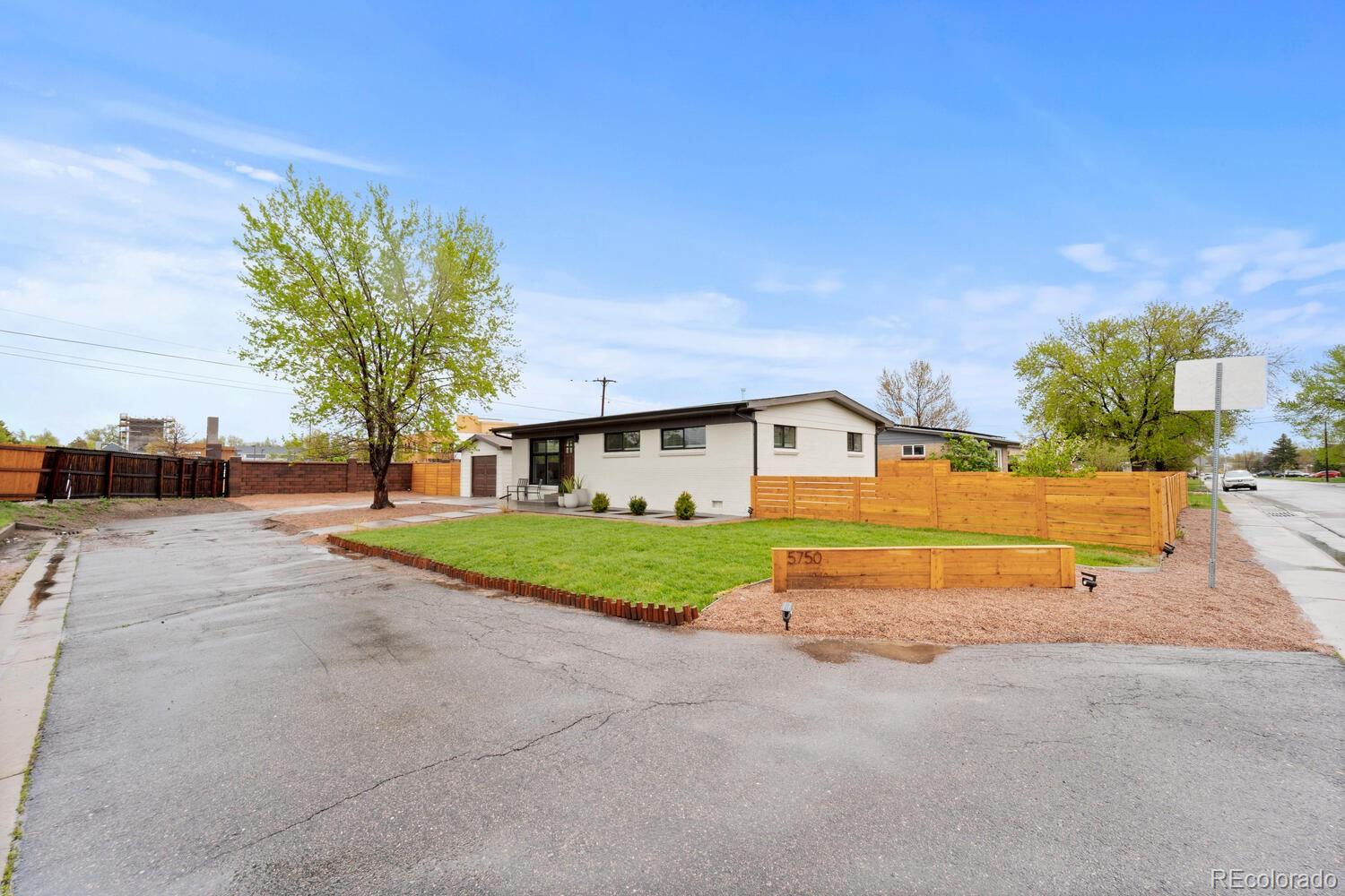 Single-story white home with a fenced lawn, driveway, and 5750 street marker.