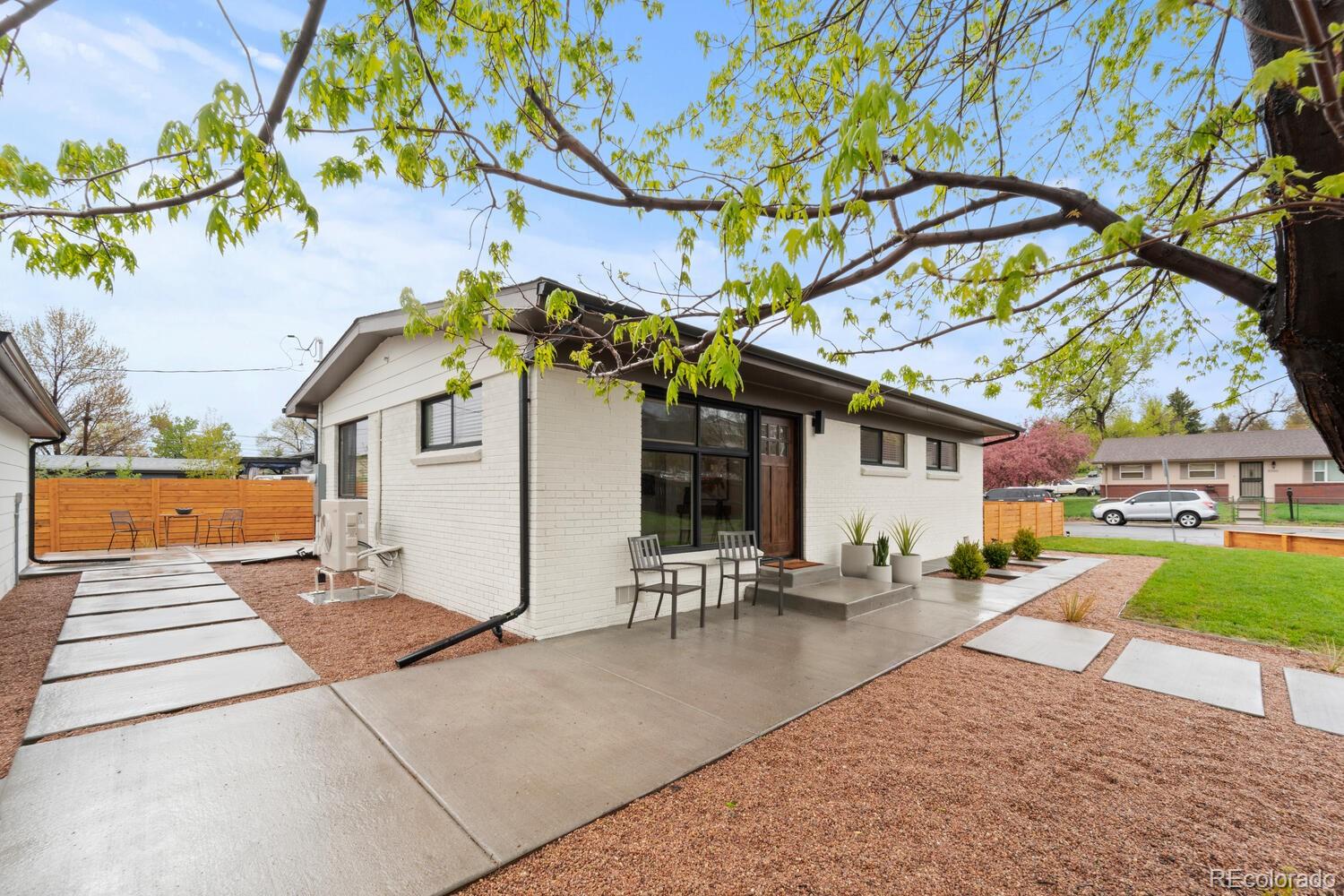 White-brick single-story home with a patio, concrete walkways, and landscaped yard.