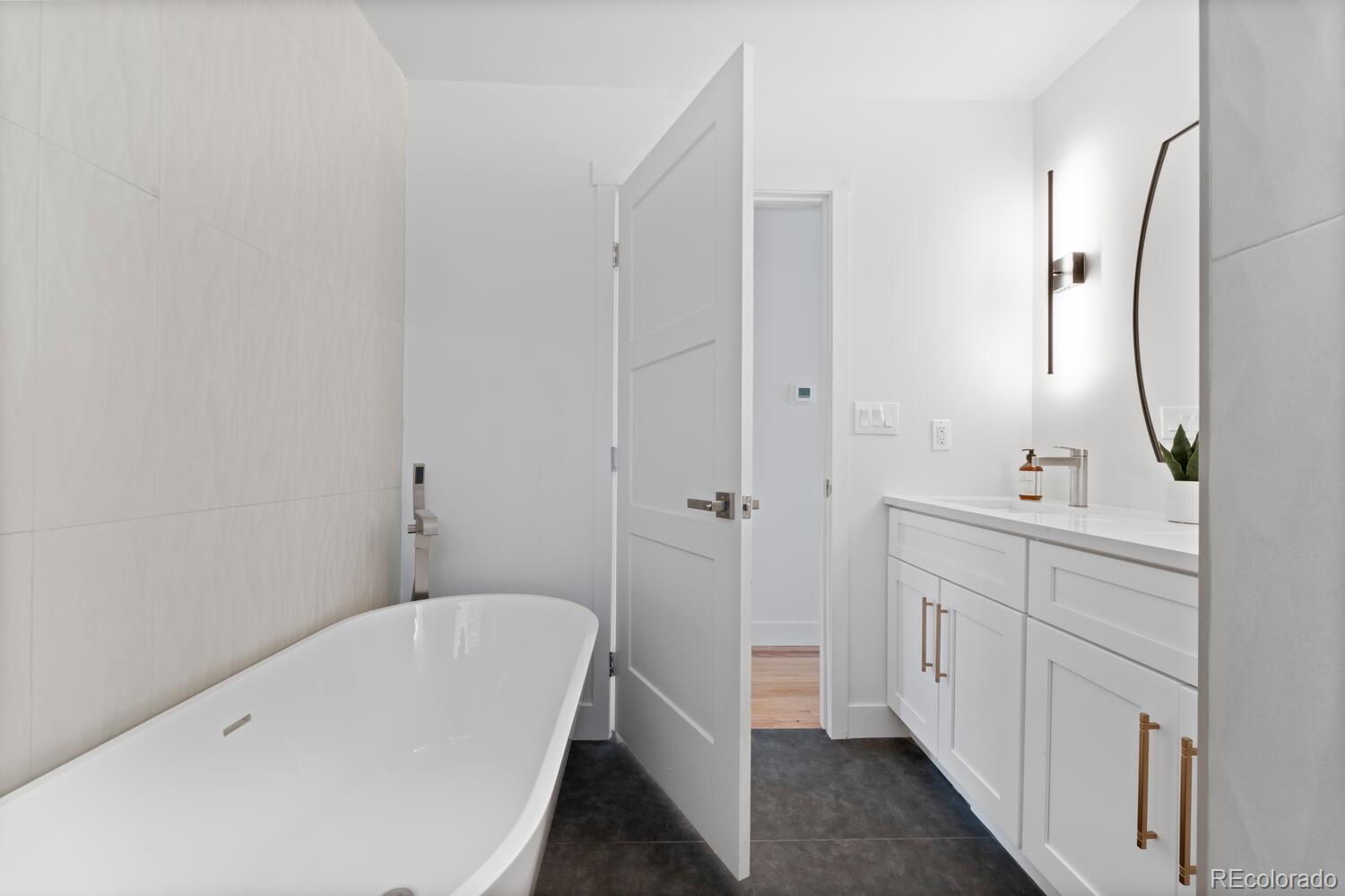 Modern bathroom with a freestanding tub and white vanity with brass pulls.