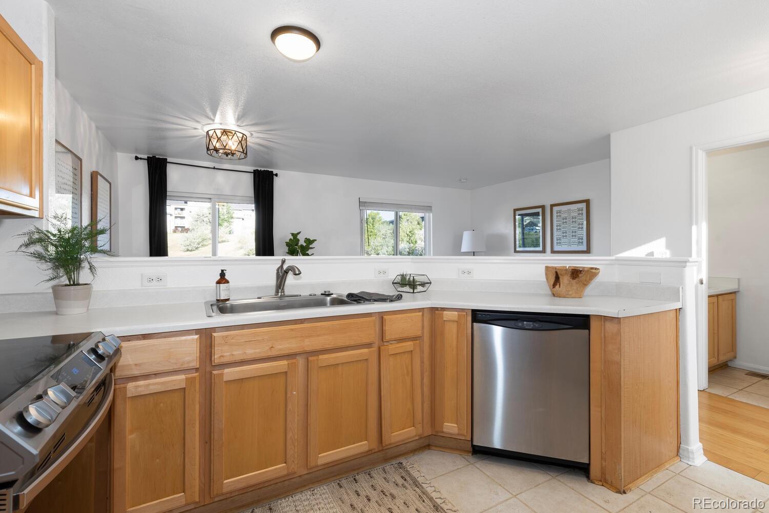 Kitchen with honey-toned cabinets, white counters, and a stainless steel dishwasher.