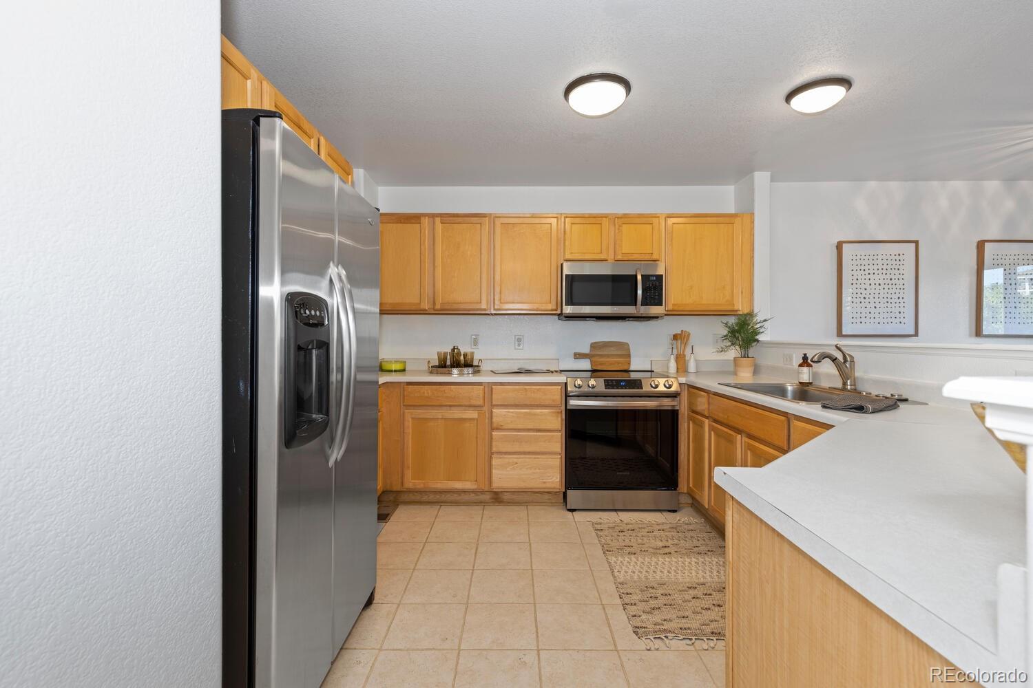Kitchen with honey-colored wood cabinets, stainless-steel appliances, and a light countertop peninsula.