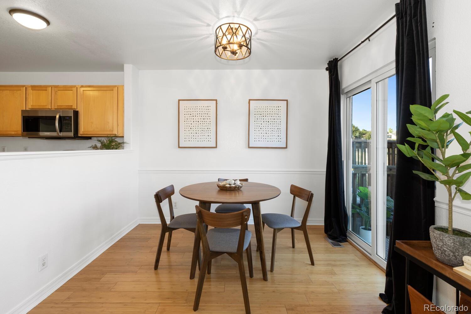 Dining area with a round wooden table, kitchen pass-through, and sliding glass door.