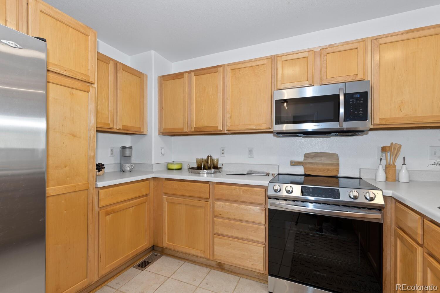 Kitchen with honey-colored wood cabinets, white countertops, and stainless-steel appliances.