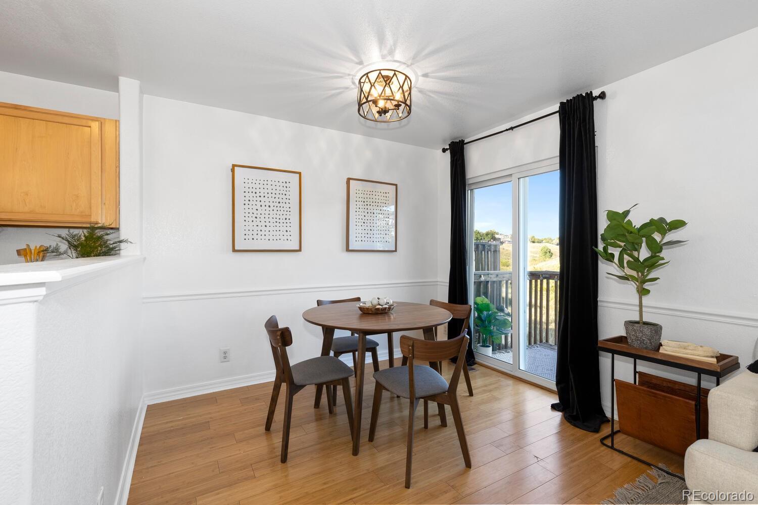 Dining area with a round wooden table beside sliding glass doors to a deck.