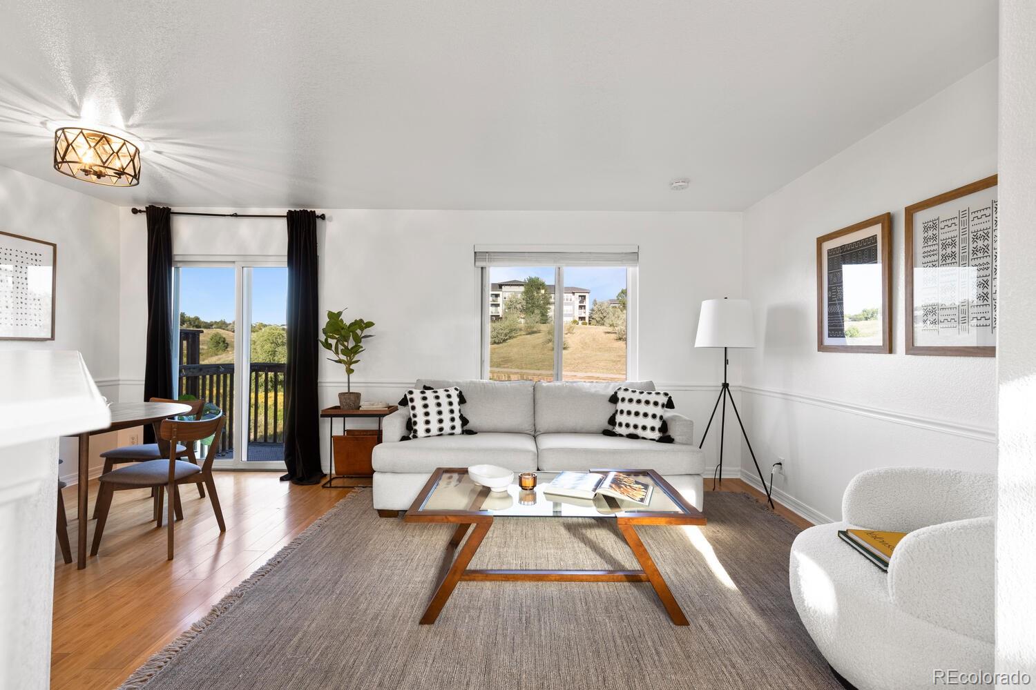 Living room with a white sofa, glass-top coffee table, hardwood floors, and sliding doors to a balcony.
