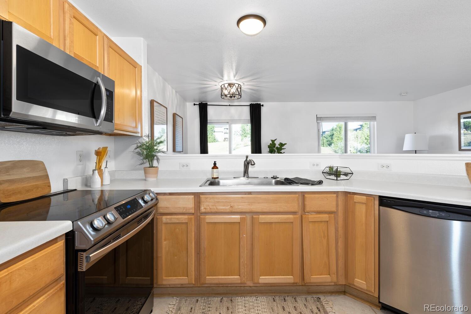 Kitchen with honey-colored cabinets, white countertops, and stainless steel appliances.