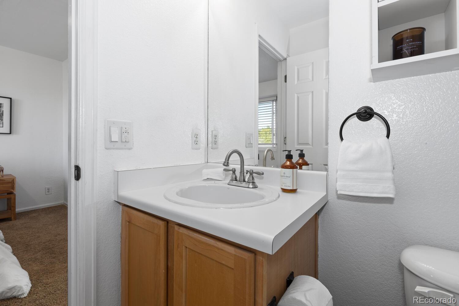 Bathroom vanity with a wood cabinet, white countertop, oval sink, and large mirror.