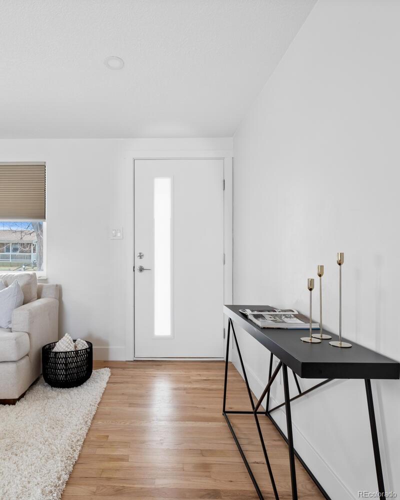 Bright entryway with a white front door, black console table, and hardwood floors.