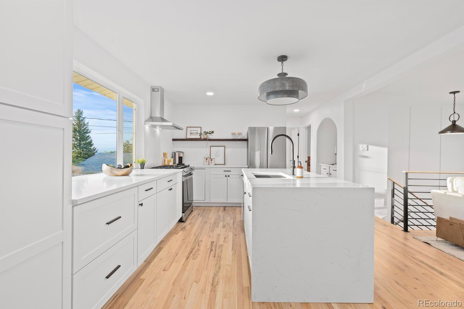Bright white kitchen with a large island, stainless appliances, and light wood floors.