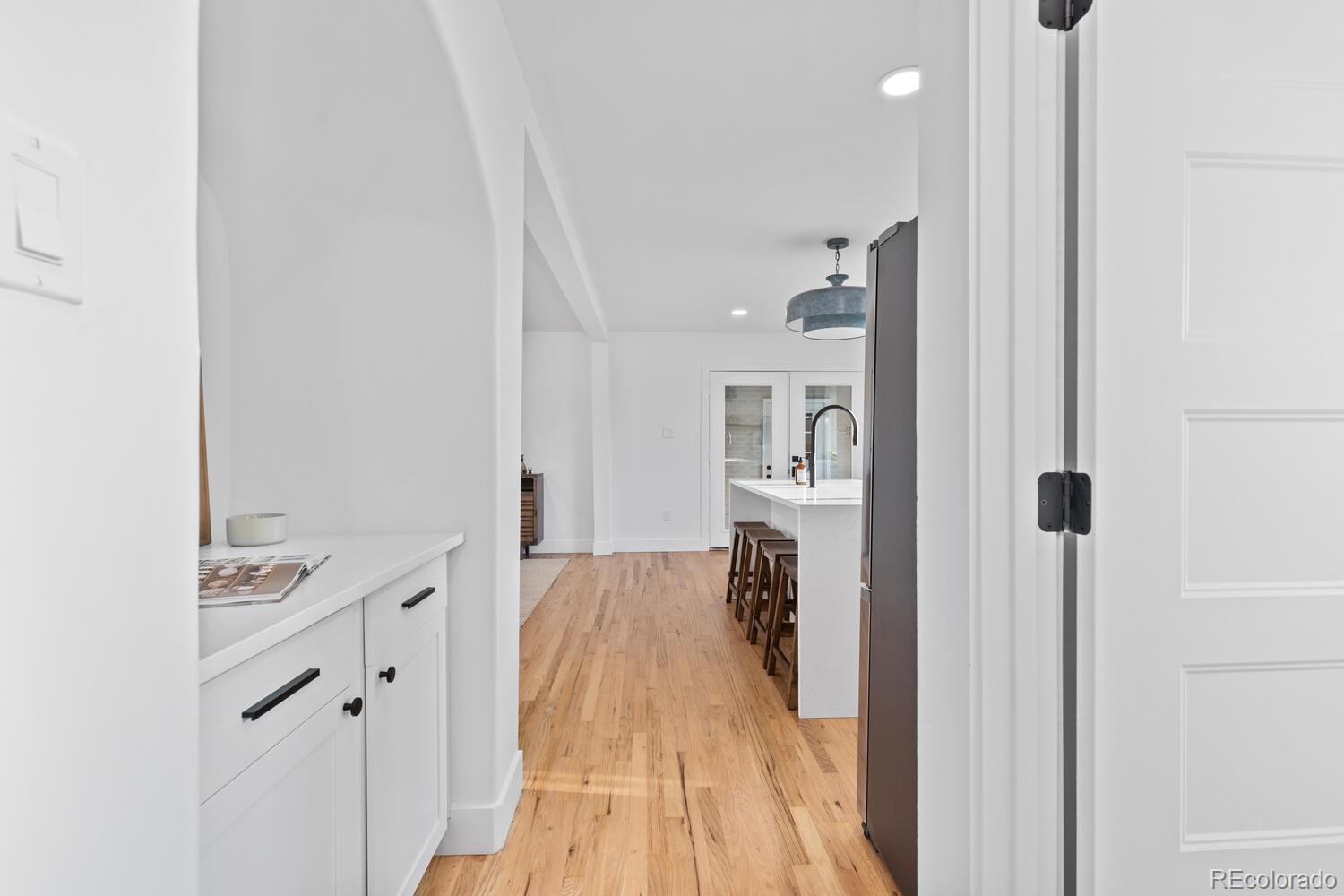 Bright white kitchen with a large island, bar stools, and light hardwood floors.