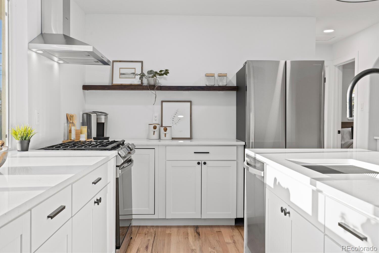 Bright white kitchen with stainless appliances, a gas range, and a large island sink.