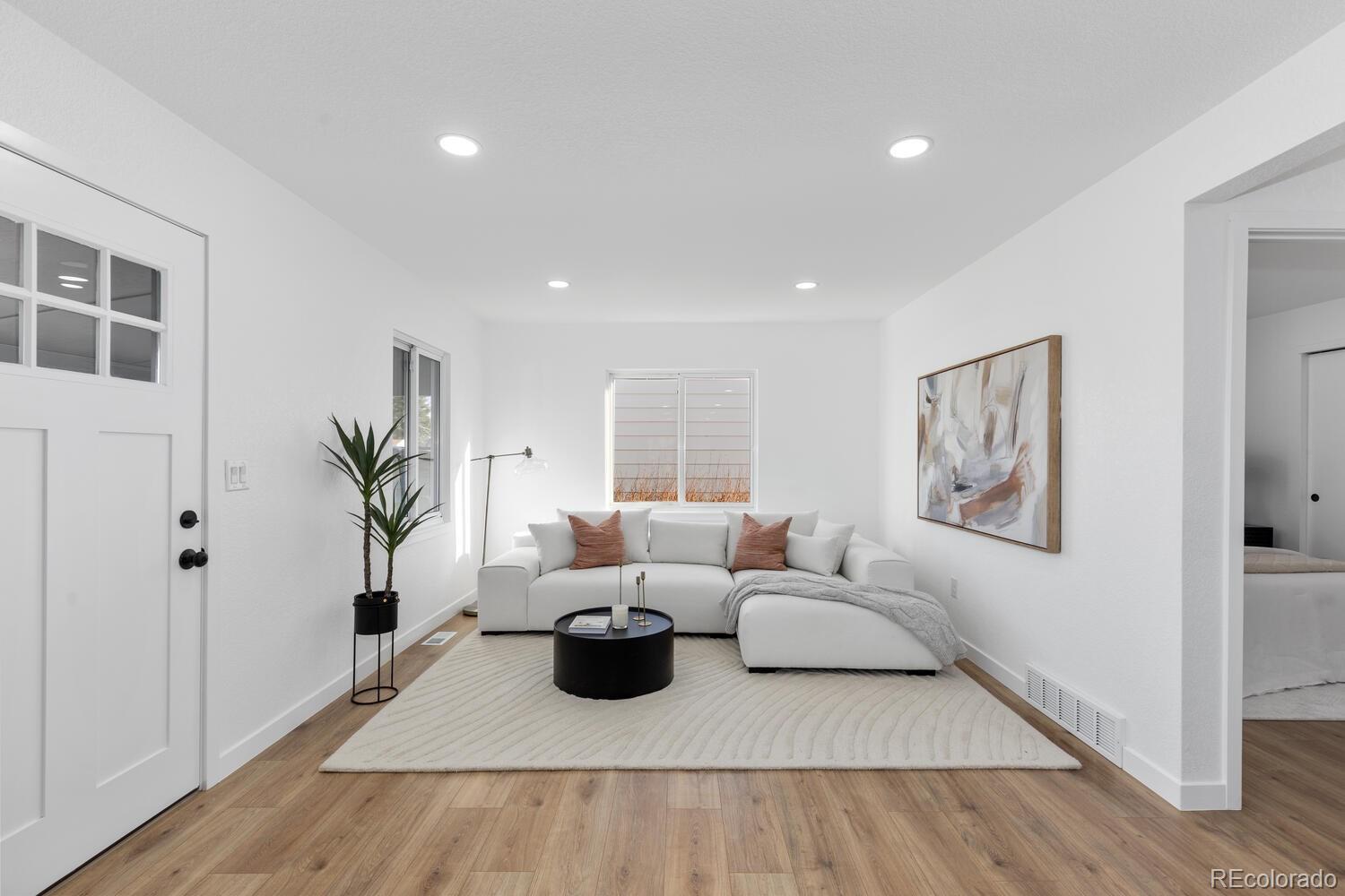 Living room with a white sectional, black round coffee table, and light wood floors.