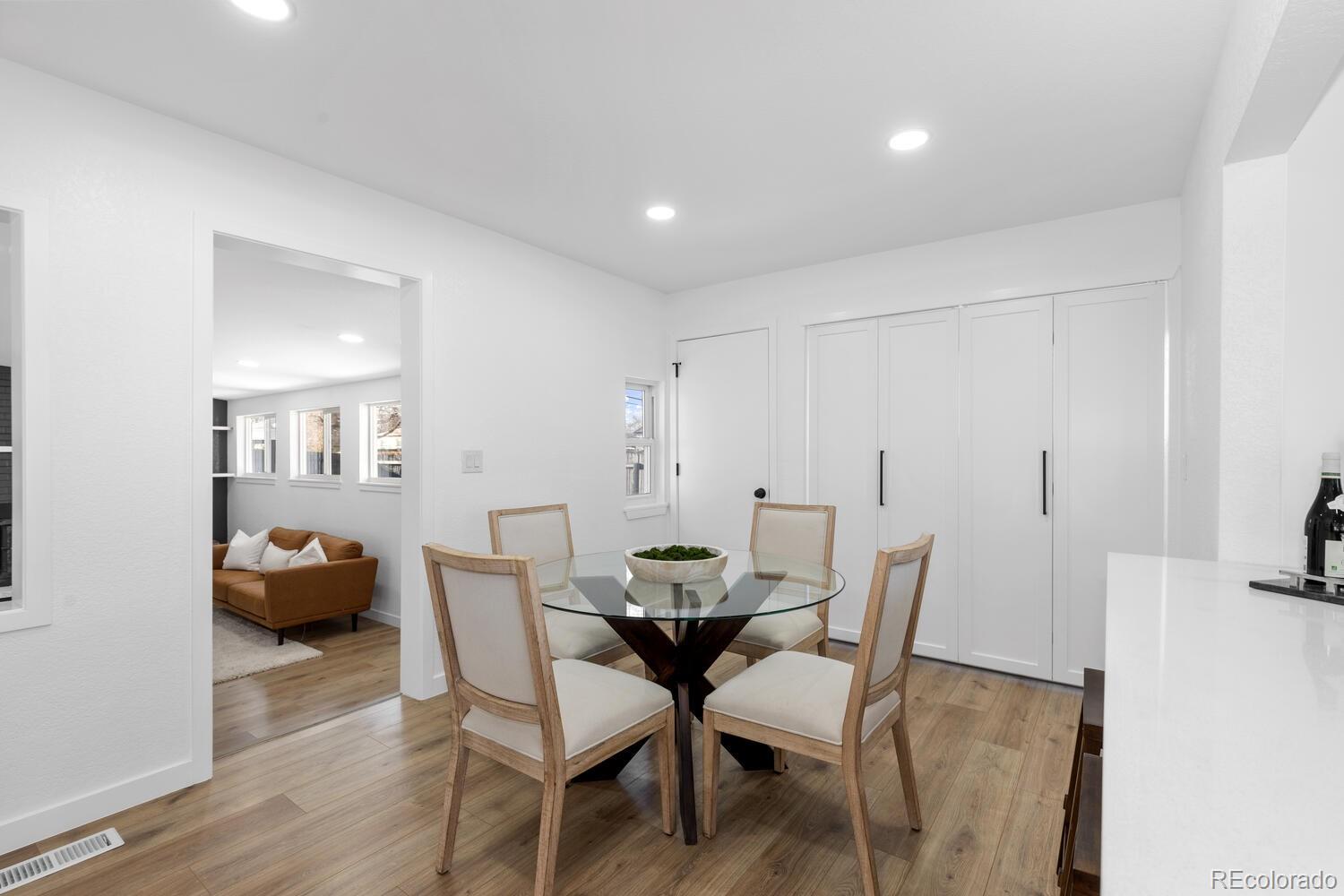 Furnished dining room with a round glass table, four chairs, and a view into the living room.