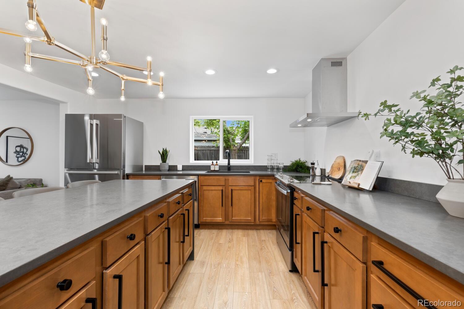 Kitchen with warm wood cabinets, gray countertops, stainless steel appliances, and a large island.