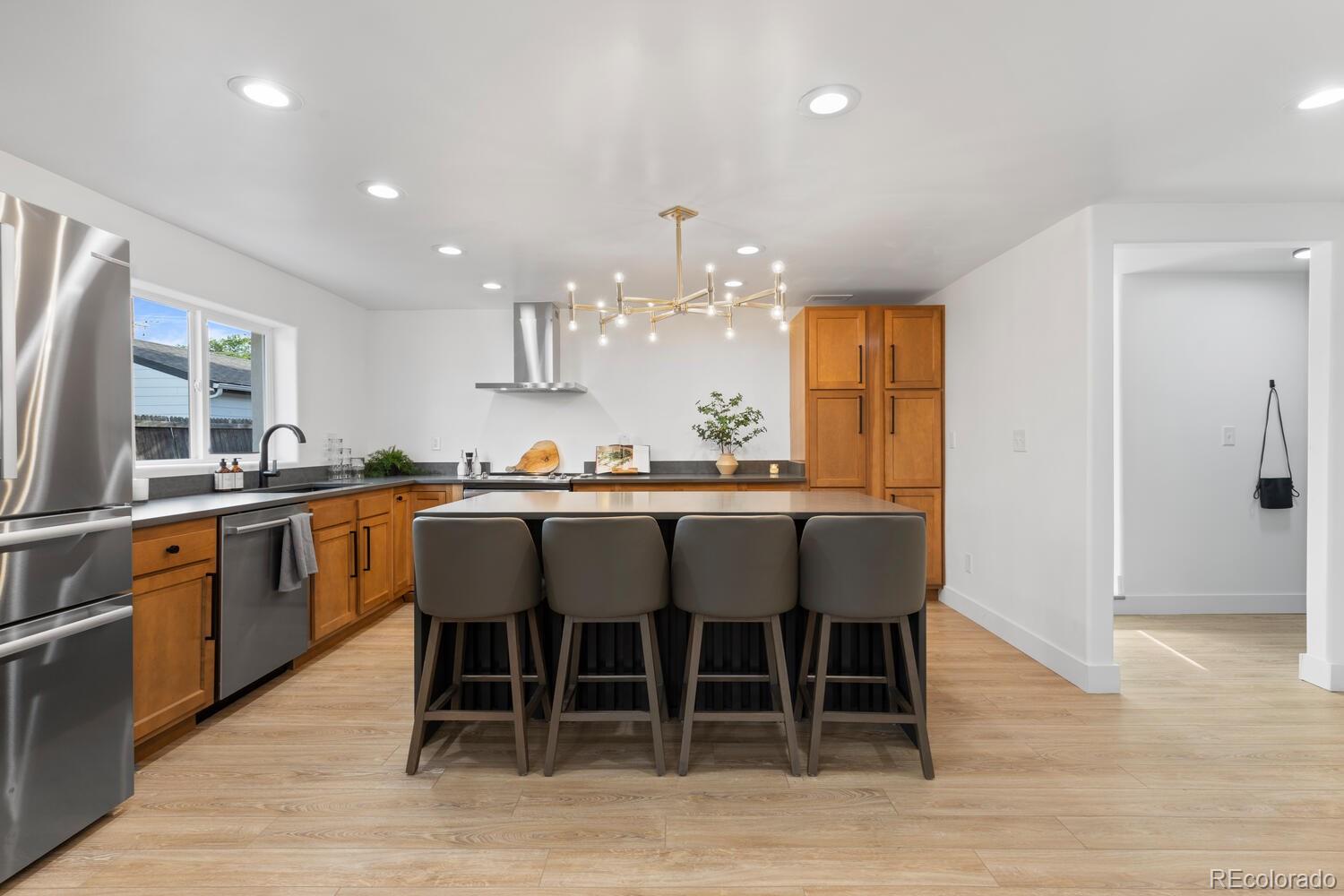 Kitchen with wood cabinets, stainless appliances, and a large island with four bar stools.