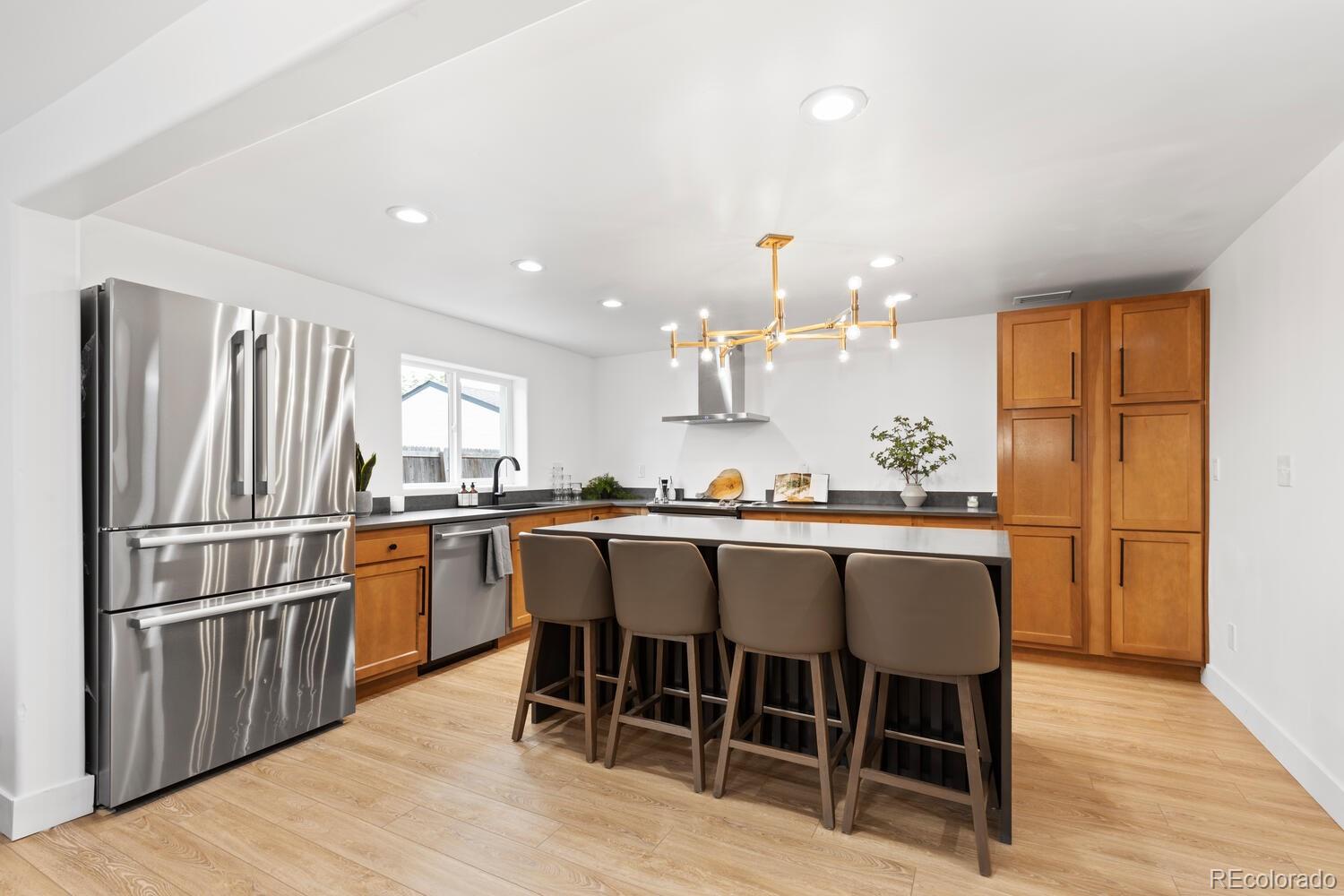 Modern kitchen with warm wood cabinets, stainless appliances, and a large island with four bar stools.