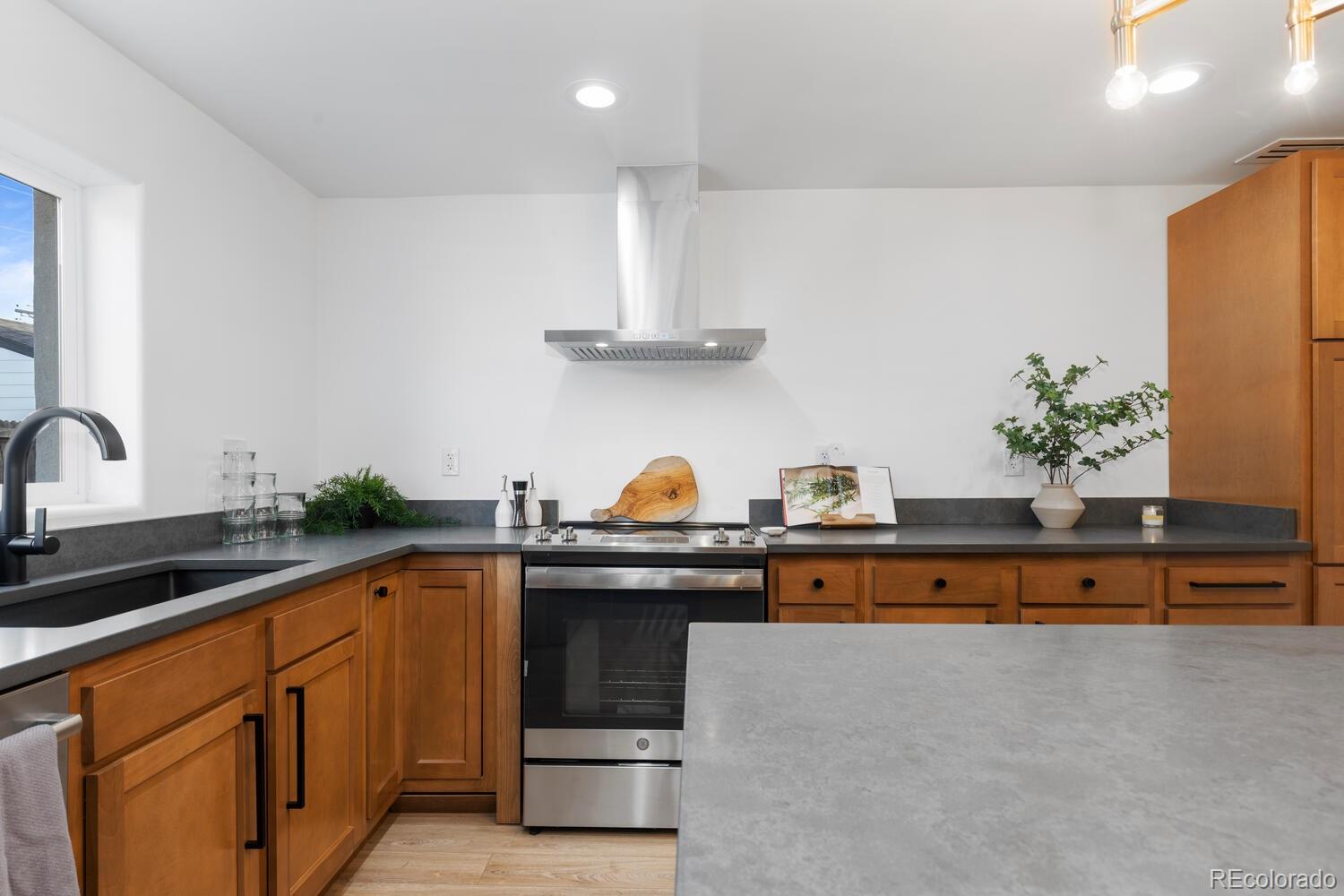 Kitchen with warm wood cabinets, dark countertops, and a large gray island.