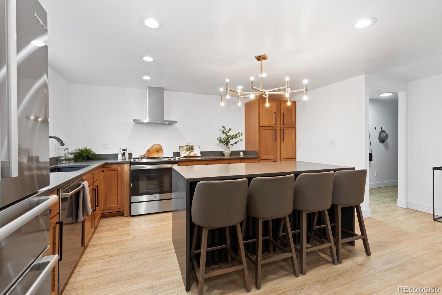 Kitchen with a large island, four bar stools, warm wood cabinetry, and stainless steel appliances.