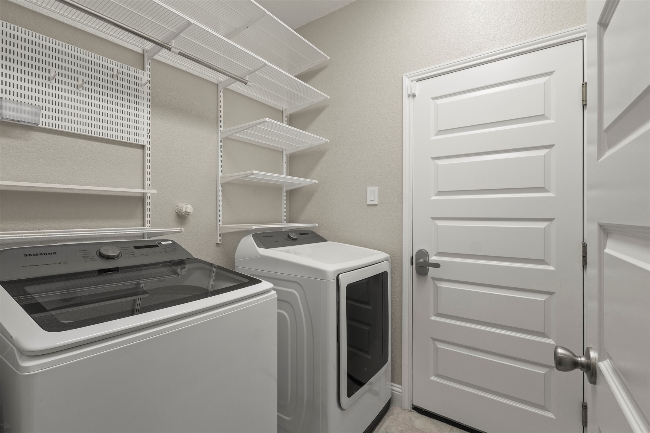 Laundry room with washer, dryer, and extensive white wire shelving.