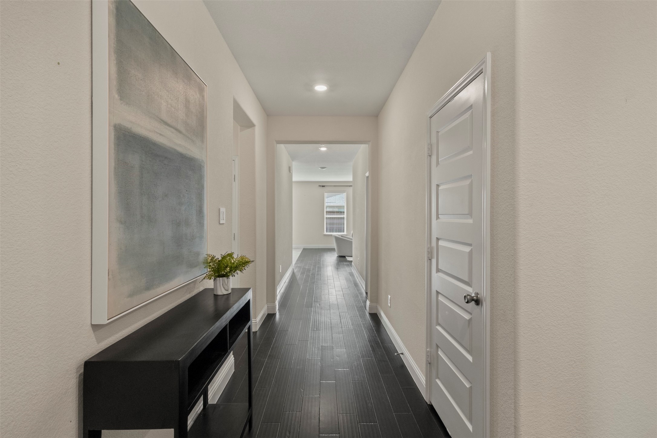 Bright hallway with dark tile flooring, a black console table, and large abstract wall art.