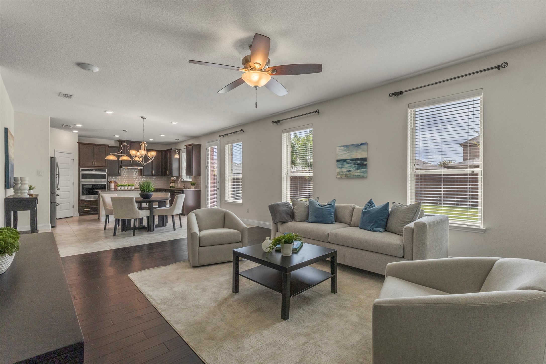 Open-plan living room with gray seating, a black coffee table, and the dining area and kitchen beyond.