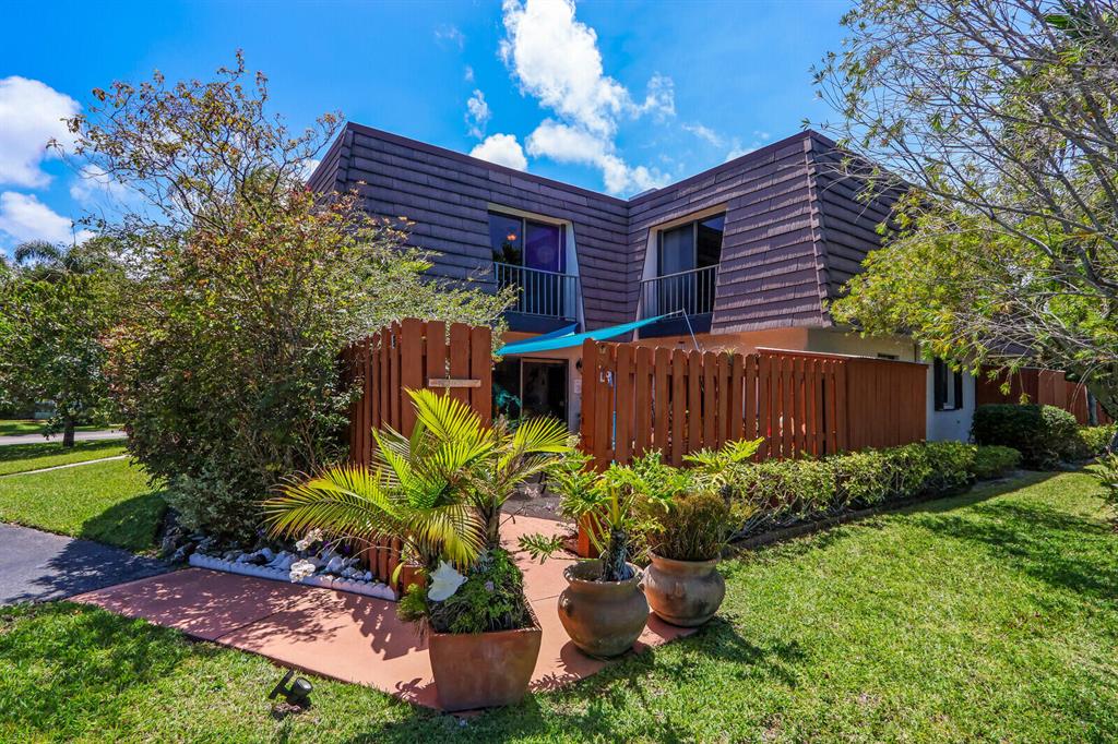 Two-story home with dark siding, upper balconies, and a fenced, landscaped entry.